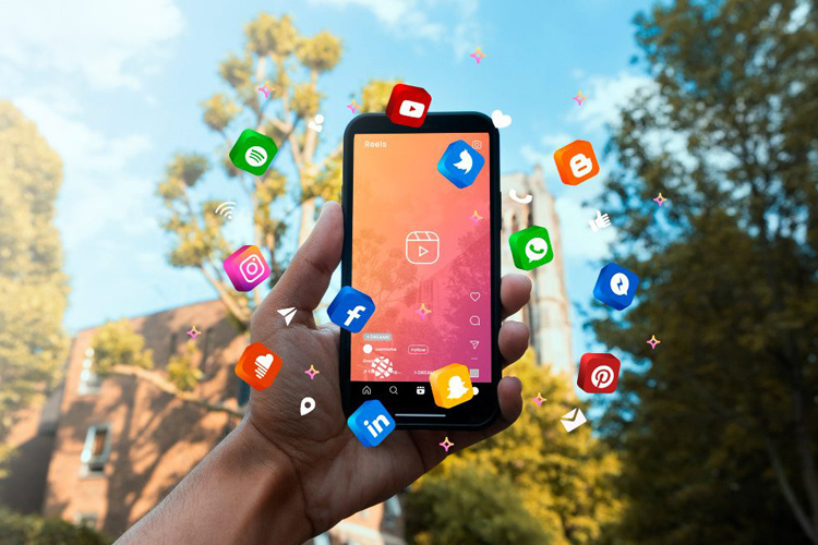 Mano que sostiene celular y allí se visualizan los iconos de varias redes sociales